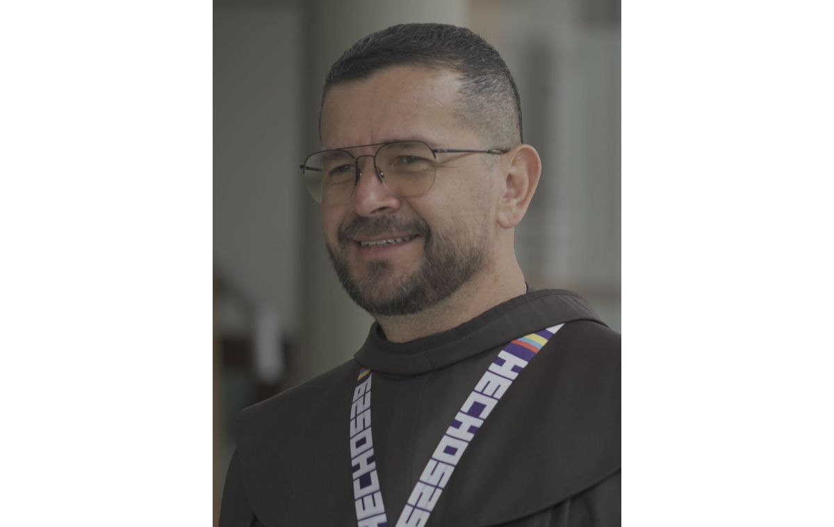 A man wearing a friar habit, lanyard, and glasses.