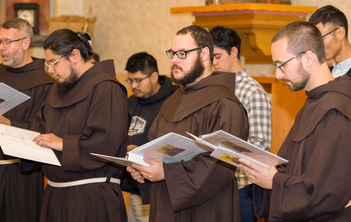 Three novices pray amongst their brothers while wearing their new habits.
