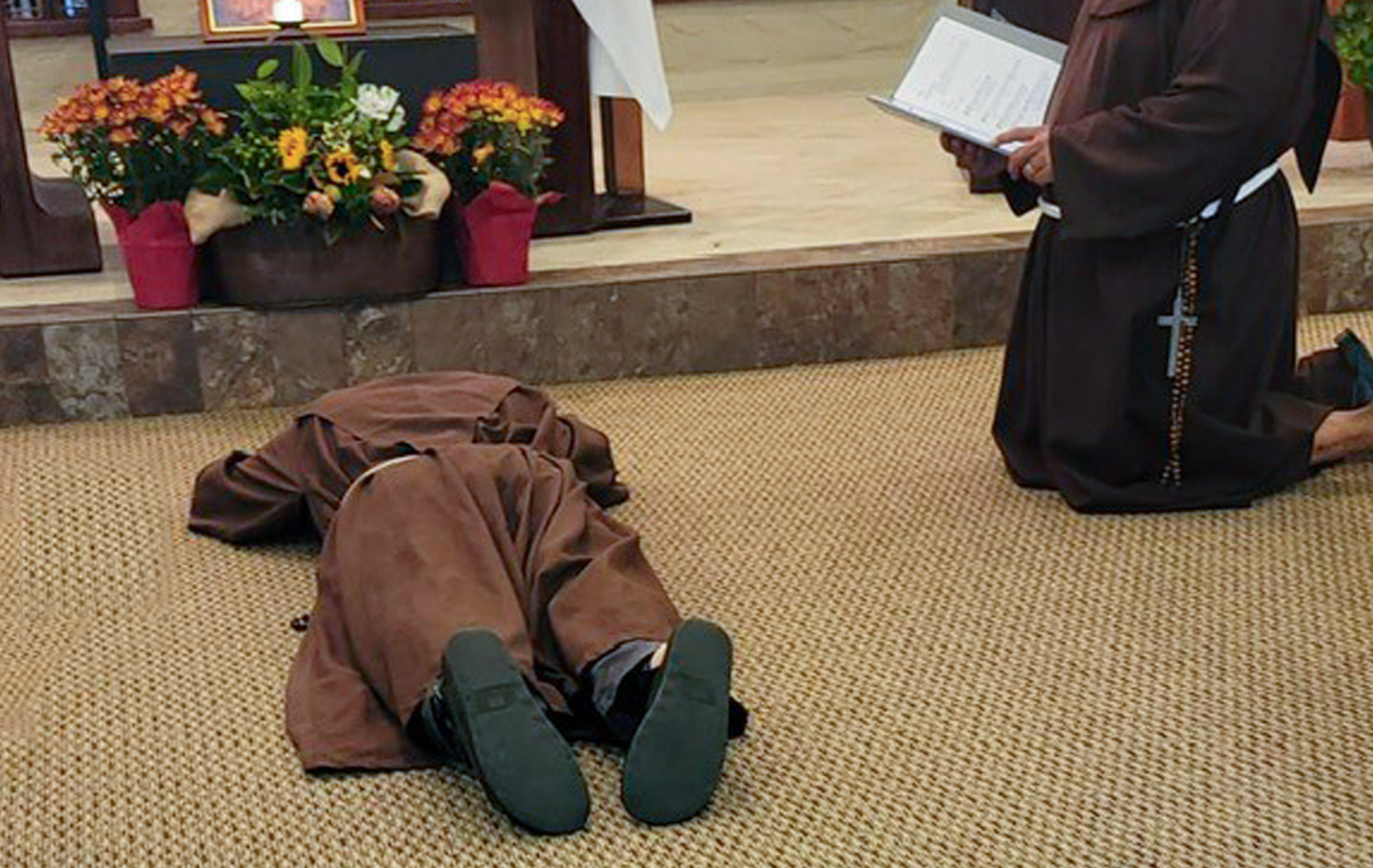A friar lies face down before the altar.