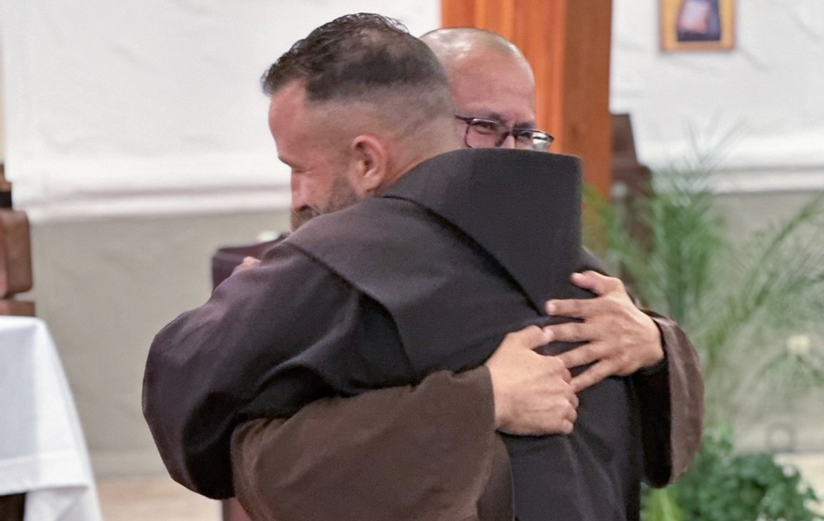 Br. Martin and another friar hug each other. Br. Martin is grinning widely.