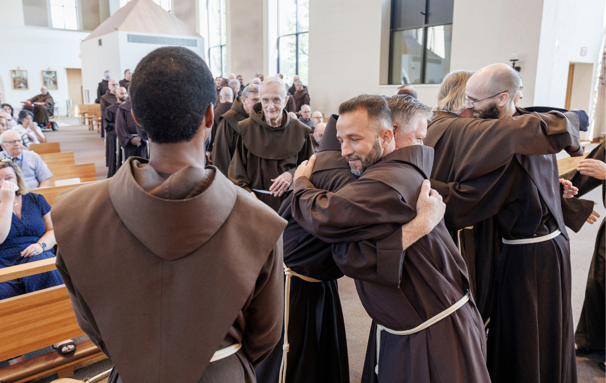 Br. Raphael Ozoude waves at the people assembled as he acknowledges their congratulations, a big smile on his face.