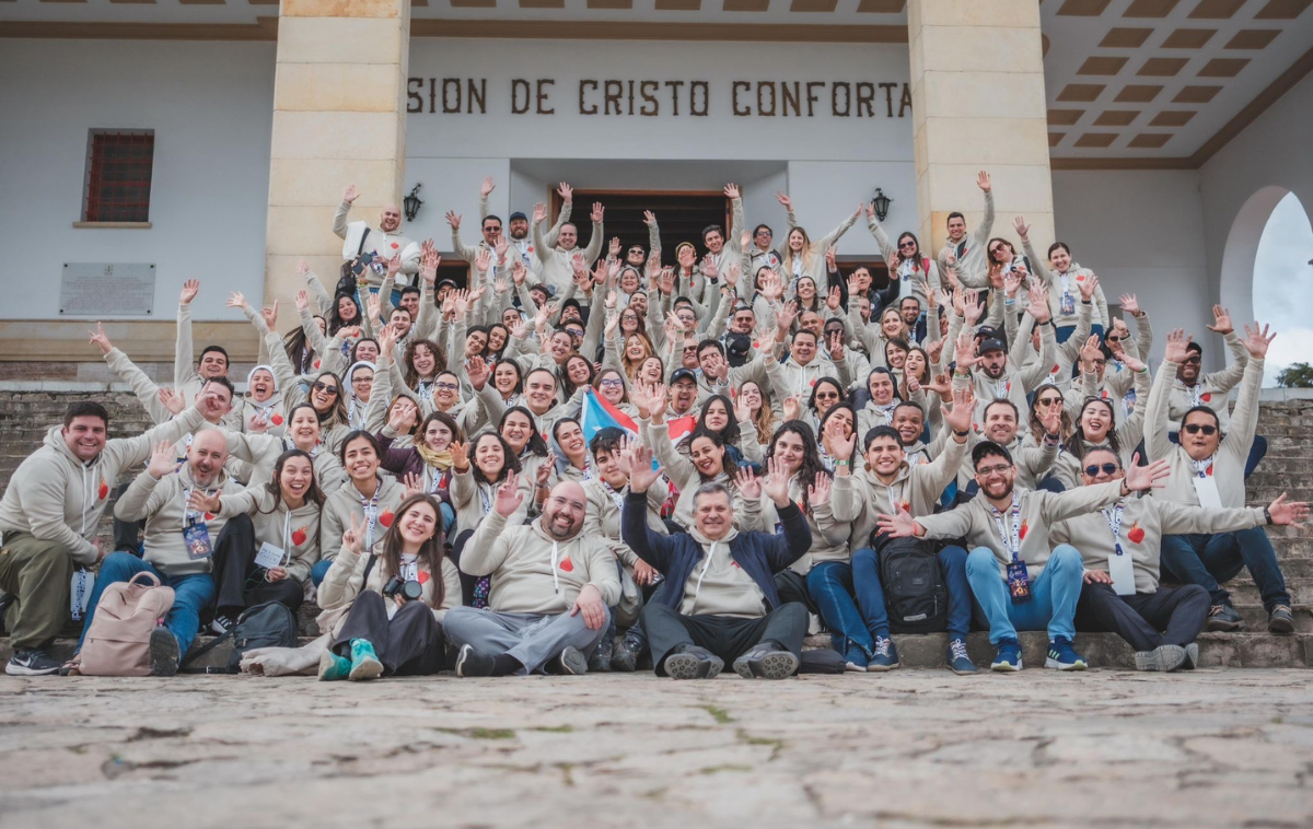 100 young people in matching sweatshirts pose together on the steps of a building.