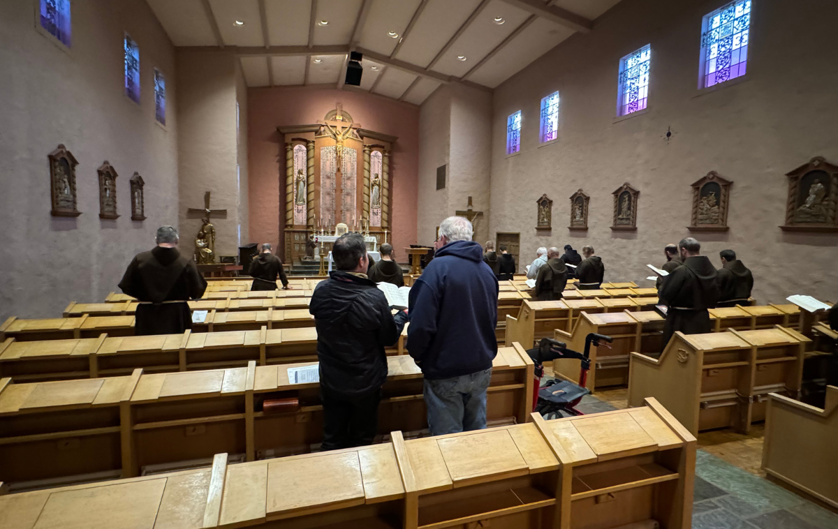 Twenty men pray together in a historic mission church