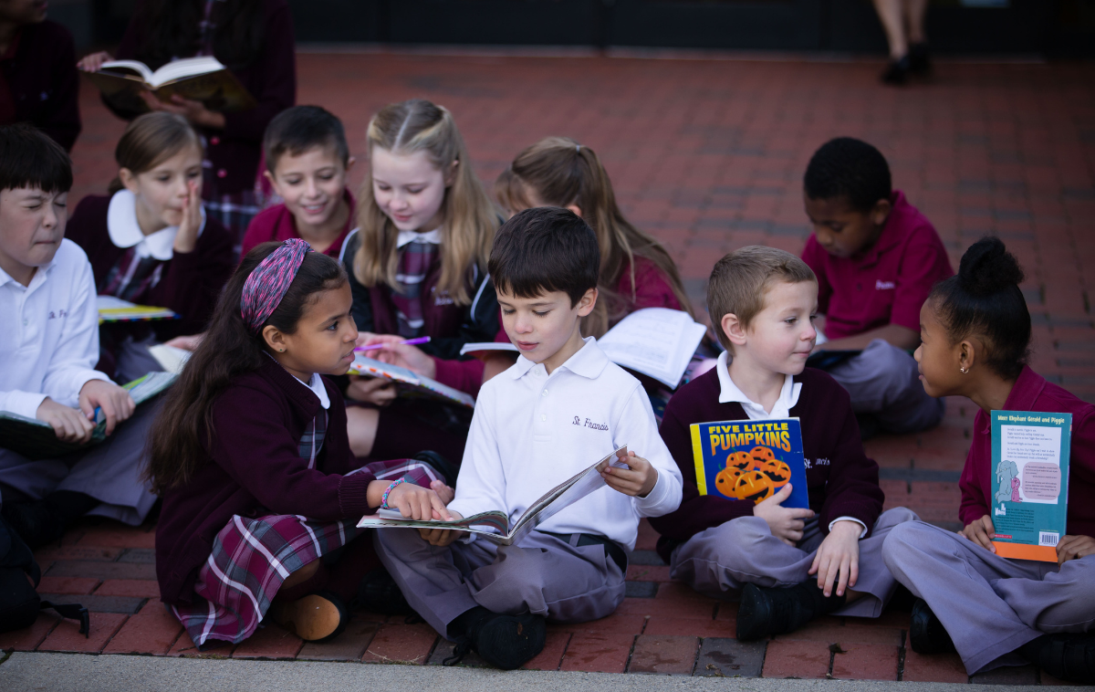 Students sit on the ground and read together