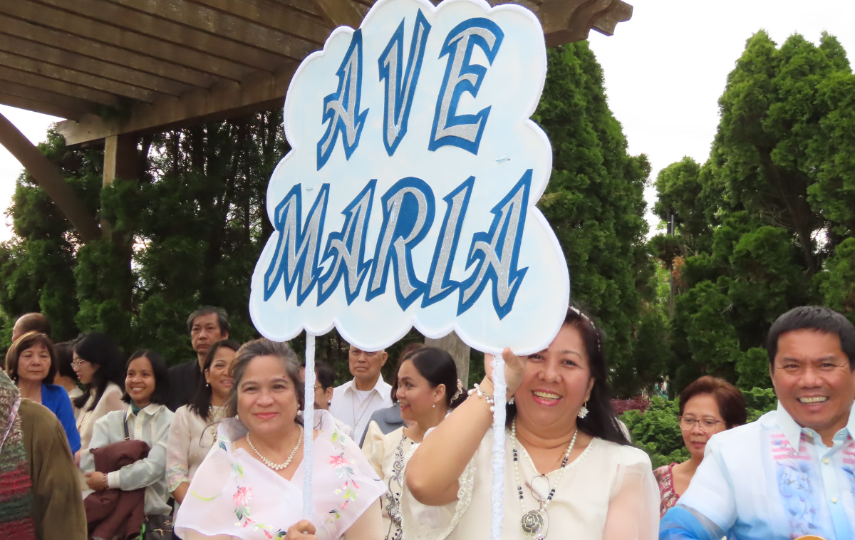 A smiling group of parishioners holds up a sign that reads 