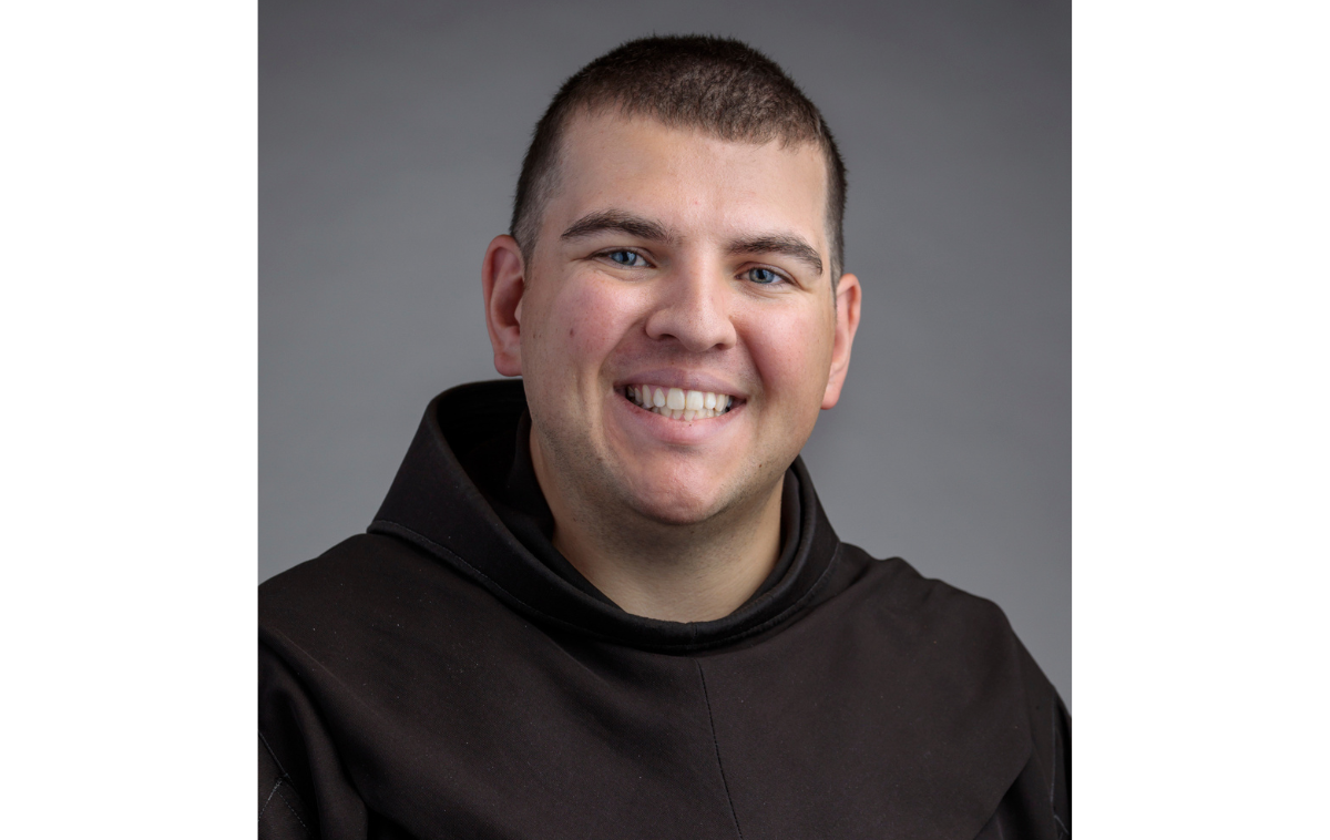 A headshot of a young smiling friar wearing his habit