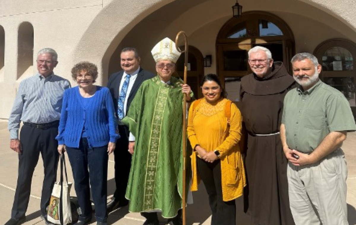 A group of seven people smile outside of a church.