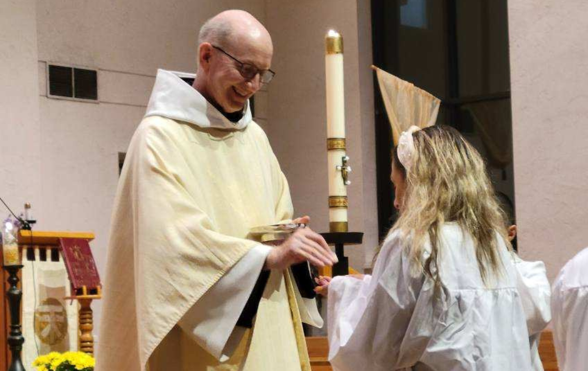 Devon Miller receives Communion from Br. Jud Weiksnar, OFM, at Easter Vigil. (Photo courtesy of Katie Daniels)
