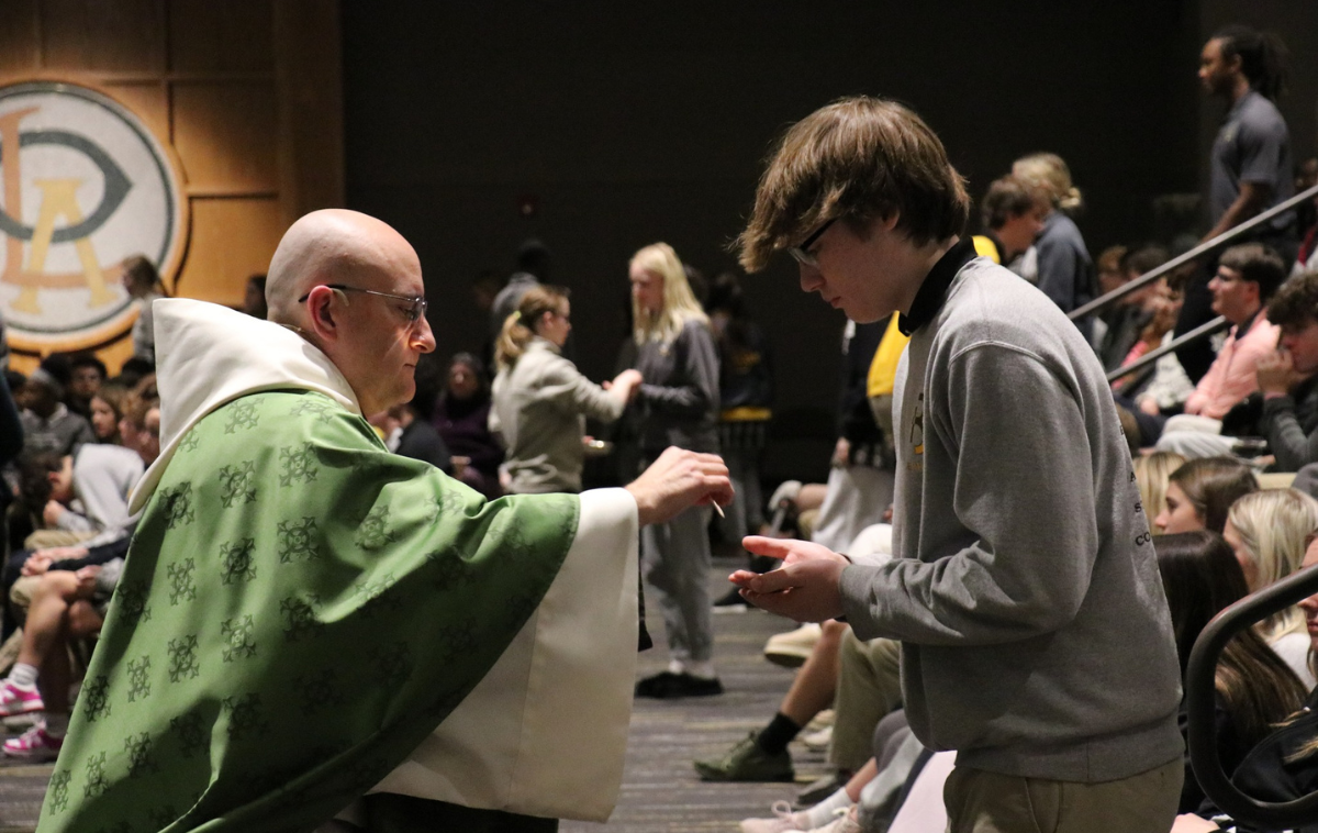 A friar presents communion to a student.