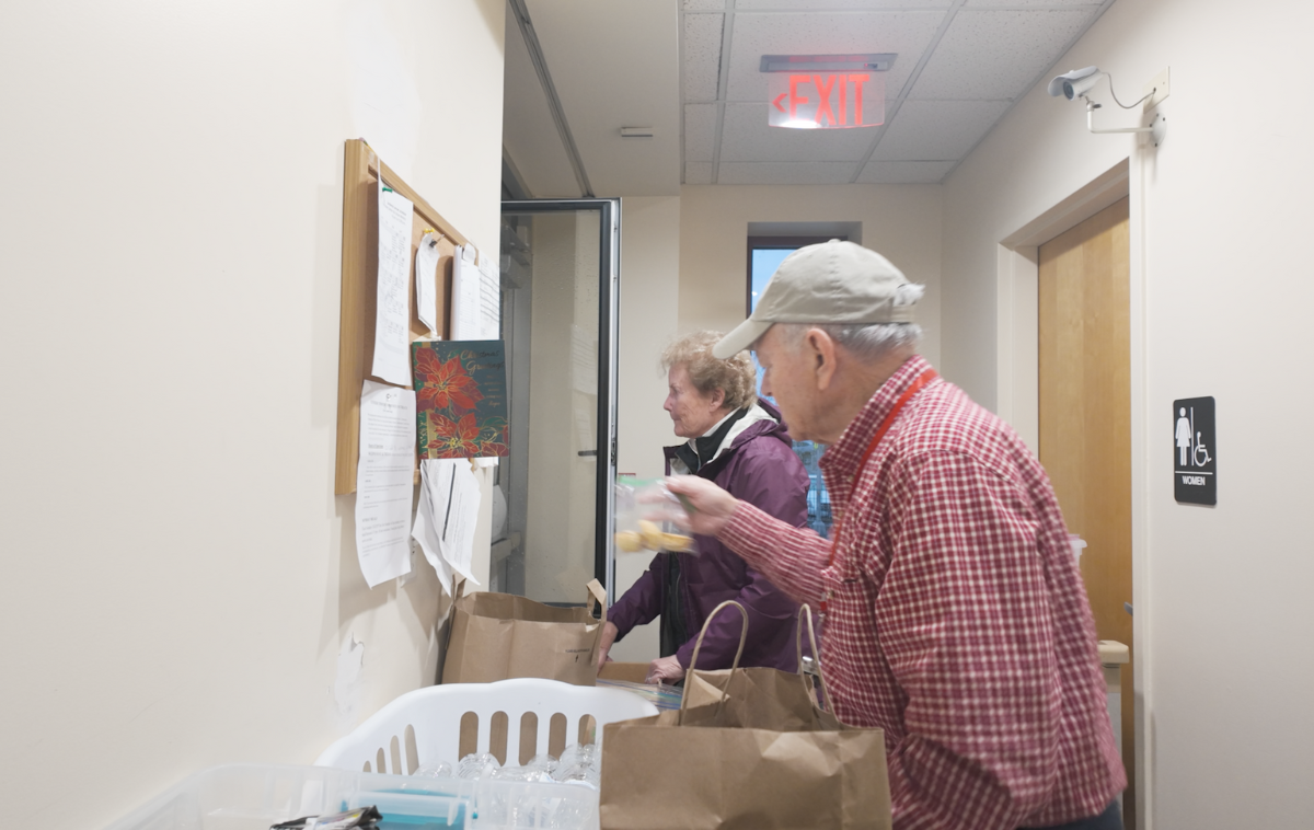 Two volunteers share bags of food with guests at the center.