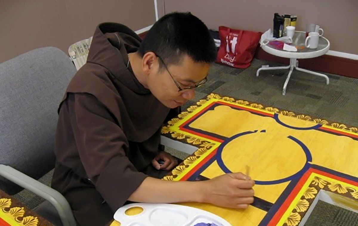 Through learning iconography, the study of symbols, themes and subject matters in visual arts, Br. Vincent Nguyen, OFM, discovered how to blend his childhood perceptions of Christ with the idea of the resurrected savior, enriching his artistic expression. Here, he paints a 9-foot San Damiano Cross for Saint Luis Rey Parish in Oceanside, California. It is the second of three he has painted. (Photo courtesy of Br. Vincent)