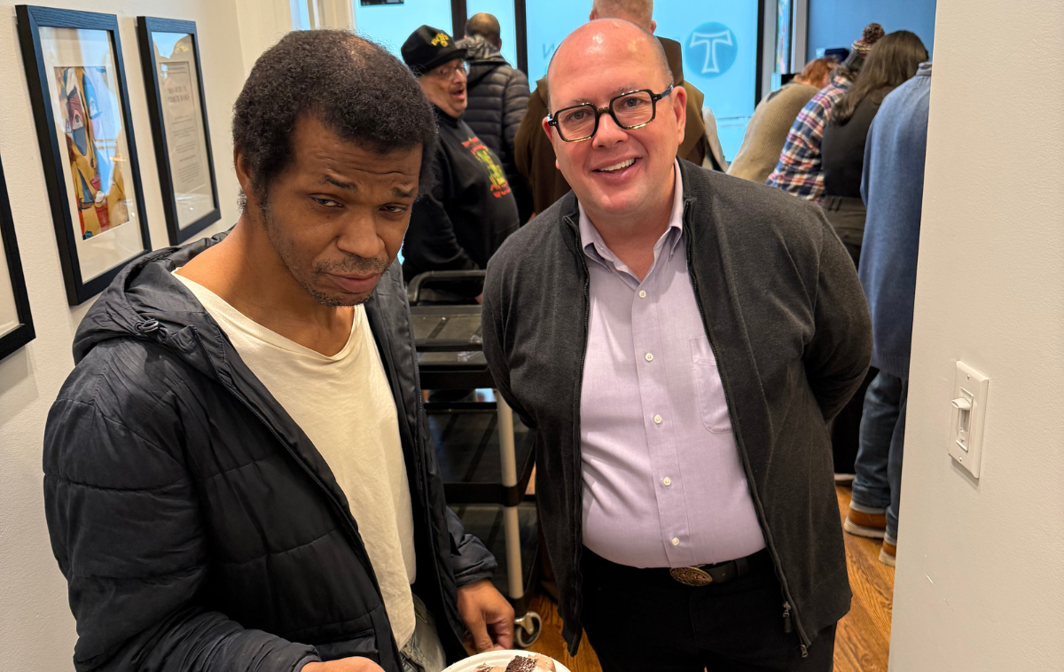 Here, finding help is a piece of cake. 360 guest Larry (left) celebrates his birthday with Br. Paul O’Keeffe, OFM, Managing Director of Franciscan 360. The artwork on the wall behind Larry, from 360’s first art exhibition, is by artist Joseph “Khari” Richardson. (Photo courtesy of Franciscan 360)