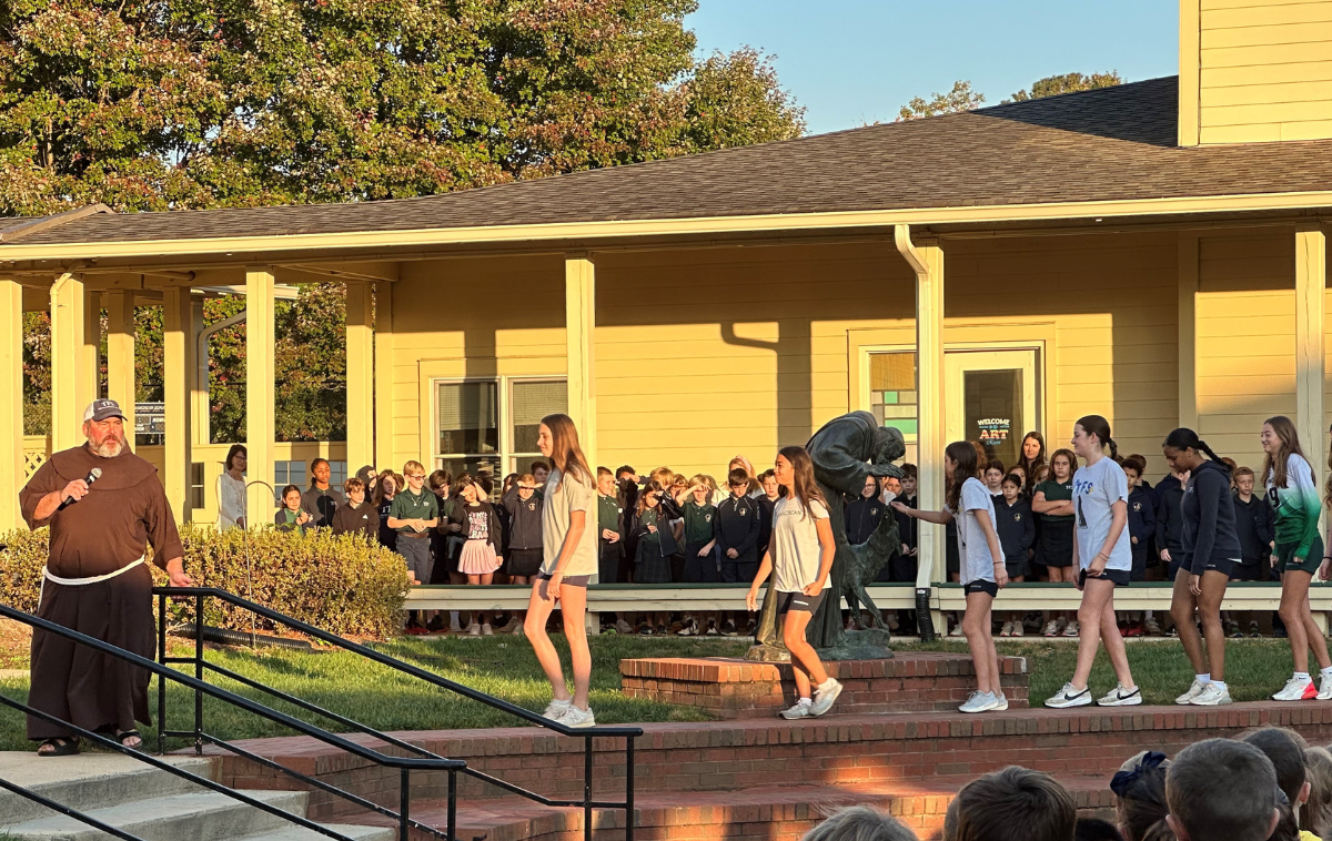 Br. James Sabak, OFM, introduces students to a TFS tradition – rubbing the nose of the statute of the Wolf of Gubbio for good luck. (Photo courtesy of Laureen Wacenske)