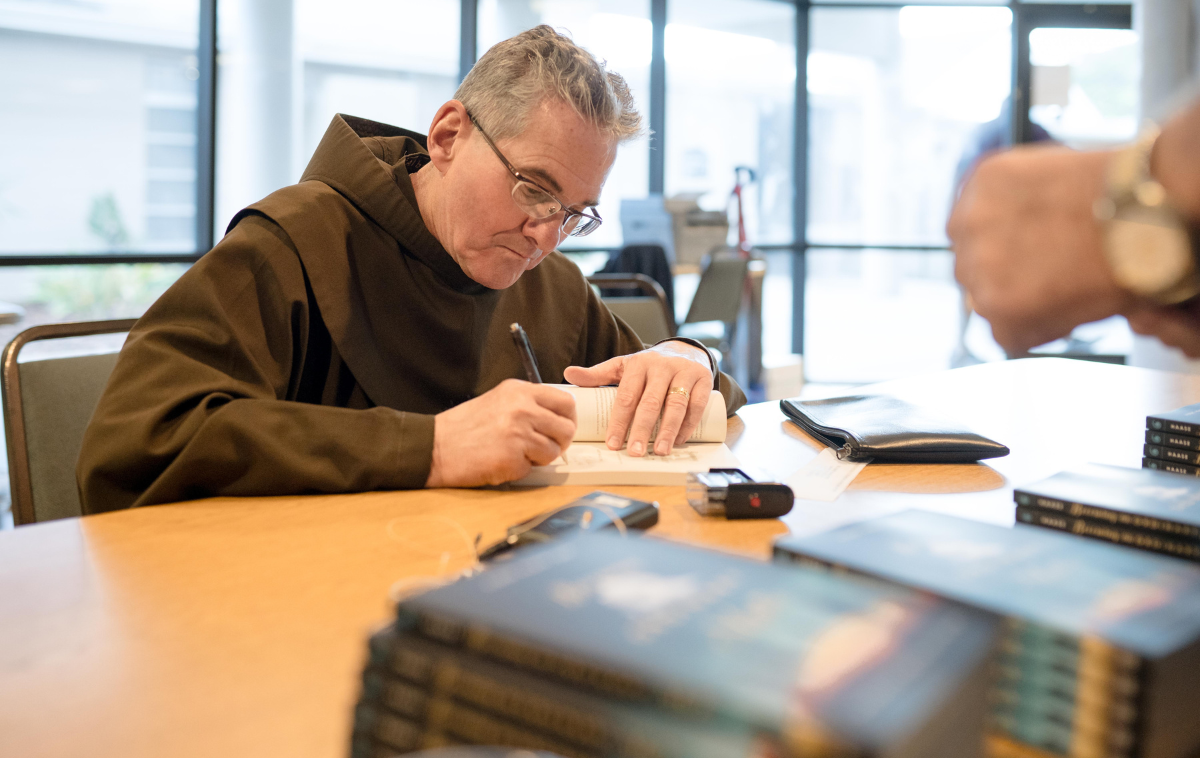 Br. Albert Haase, OFM, autographs copies of his book during a lunch break at a day of recollection at a United Methodist church in St. Petersburg, Florida, in 2023. (Photo courtesy of Br. Albert Haase, OFM)