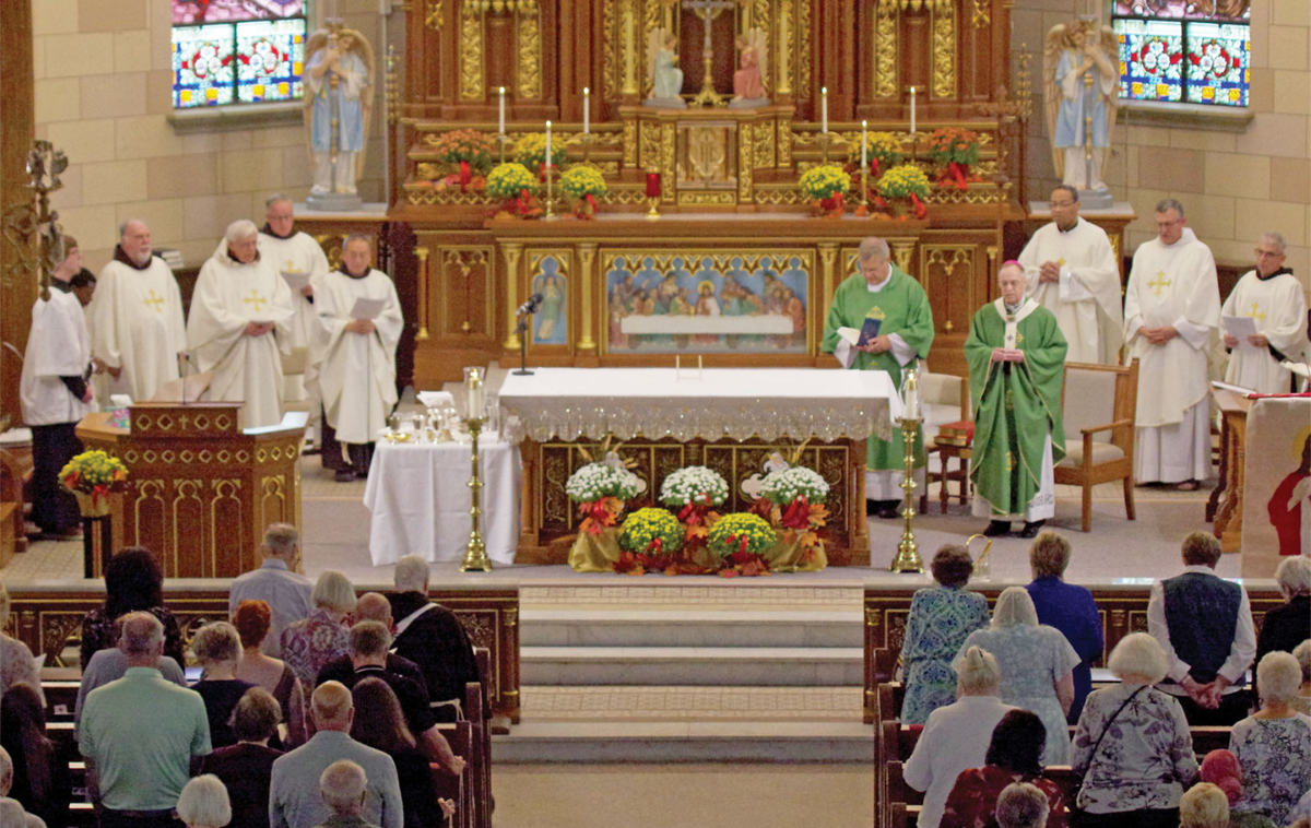 Surrounded by friars in the sanctuary of Sacred Heart of Jesus Parish in Indianapolis, Archbishop Charles C. Thompson presides at a Mass on Sept. 20, 2025, to mark the 150th anniversary of the founding of this faith community that was established with the help of Franciscans. (Photo courtesy of <span style="font-style:italic;">The Criterion</span>)