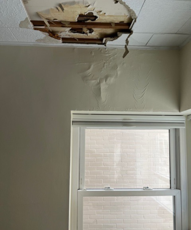 Water damage to a ceiling with a hole in it. There is a wall and a window in the frame also.