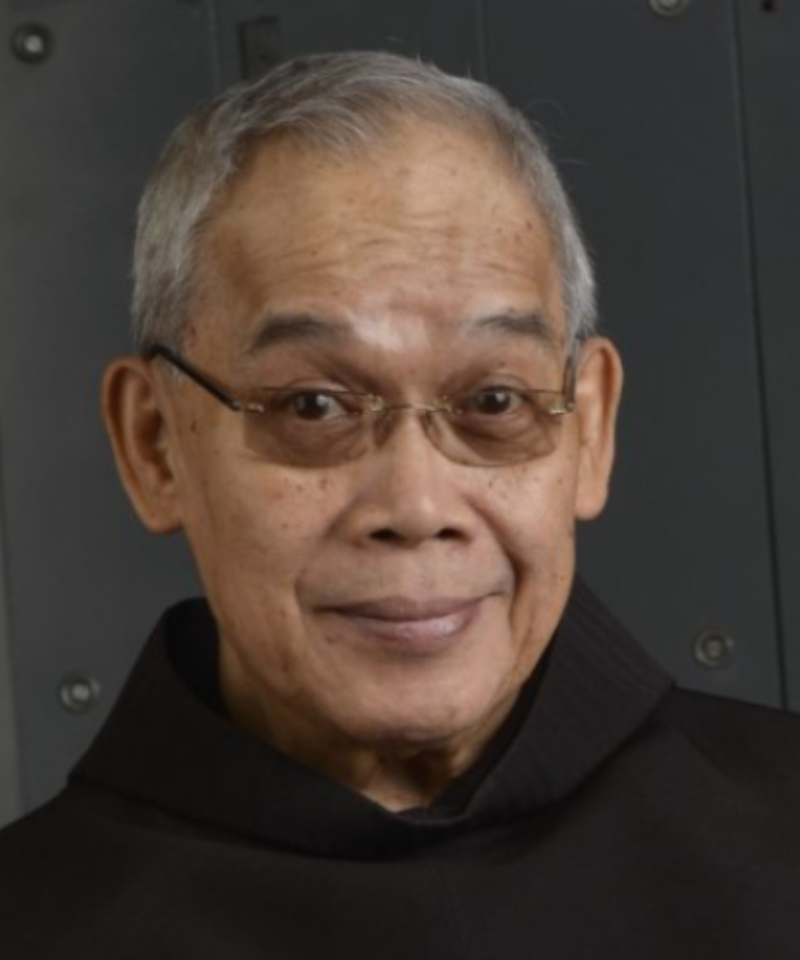 A smiling man wearing eyeglasses and a friar habit.