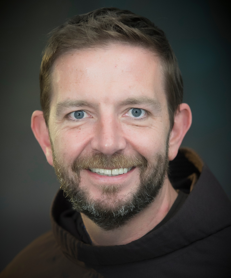 A smiling, bearded man wearing a friar habit.