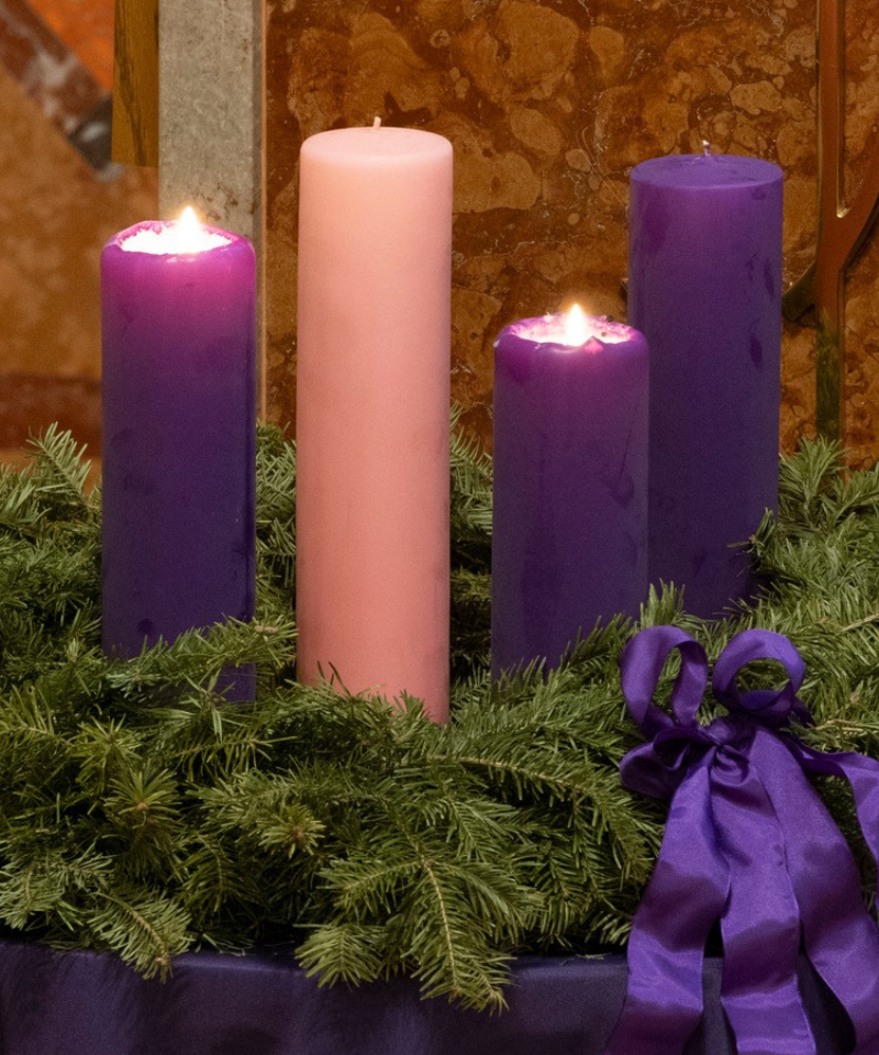 Two purple candles are lit on an Advent wreath.